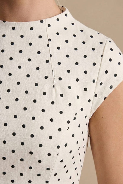 Close up of the high round neckline and cap sleeve with black dots on ivory