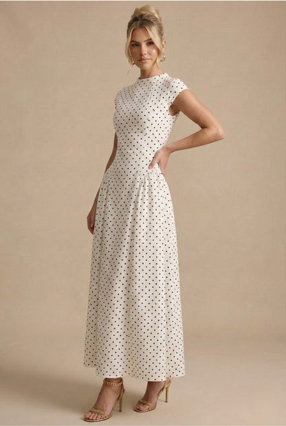 Model with hand on hip wearing the high neck polka dot maxi dress